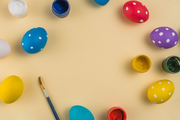 Easter eggs with paints and brush on beige table