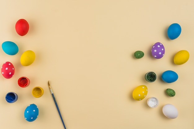 Easter eggs with paints and brush on table