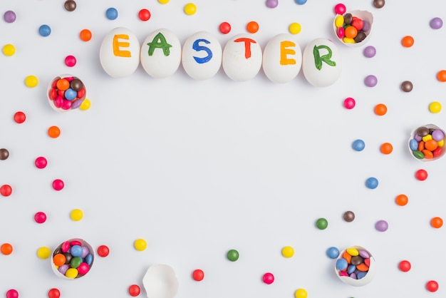 Easter inscription on eggs with candies on white table