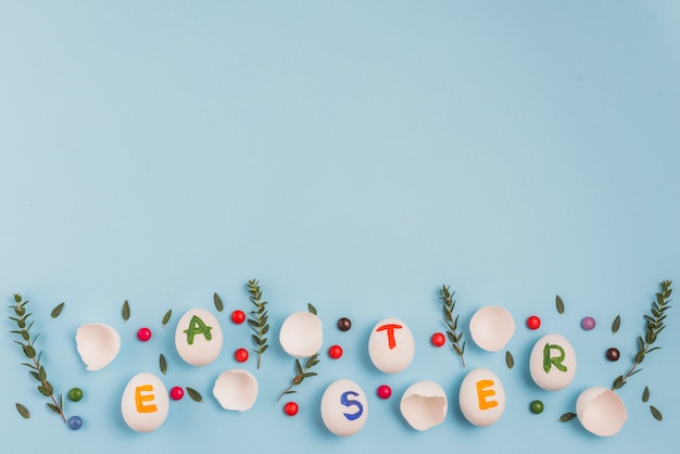 Free photo easter inscription on eggs with plant branches and candies