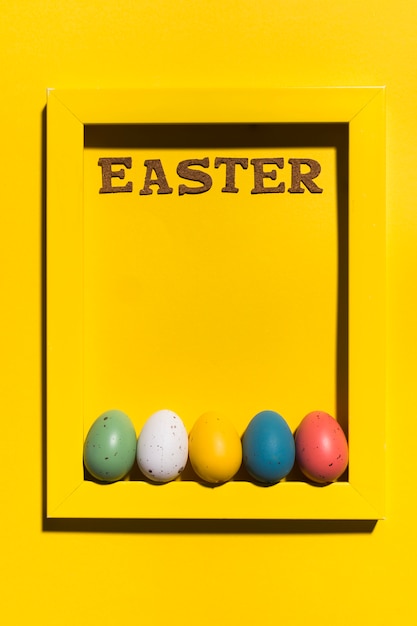 Free photo easter inscription in frame with colourful eggs