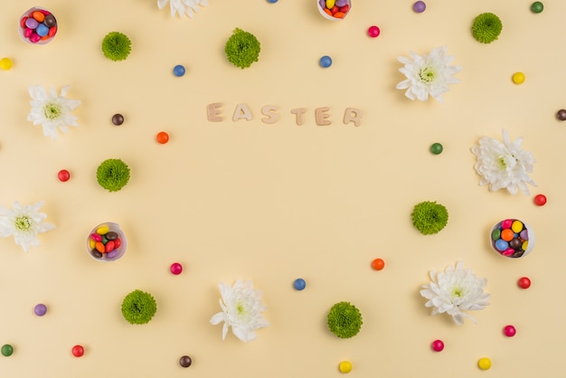 Free photo easter inscription with flowers and candies on table