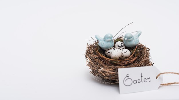 Easter inscription with quail eggs in nest on table