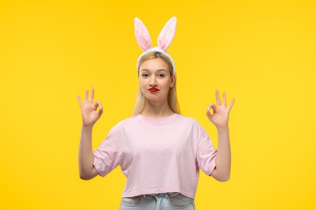 Easter lovely blonde adorable girl with pink bunny ears and red lipstick confident showing ok sign