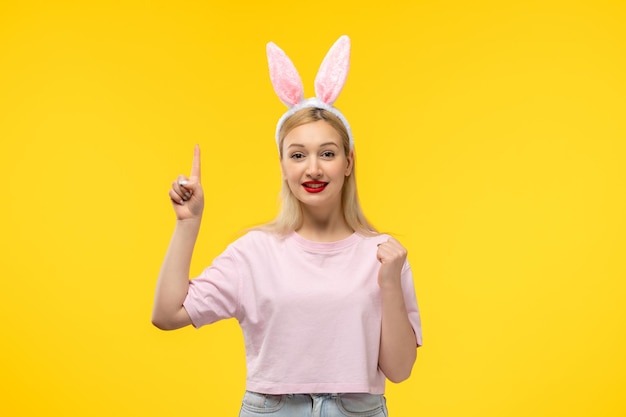 Easter lovely blonde adorable girl with pink bunny ears and red lipstick excited with fist up