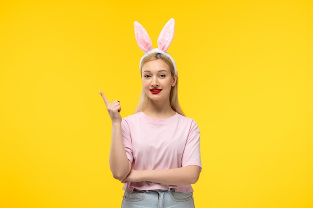 Easter lovely blonde adorable girl with pink bunny ears and red lipstick happy pointing up