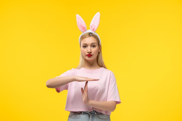 Easter lovely blonde adorable girl with pink bunny ears and red lipstick showing stop sign