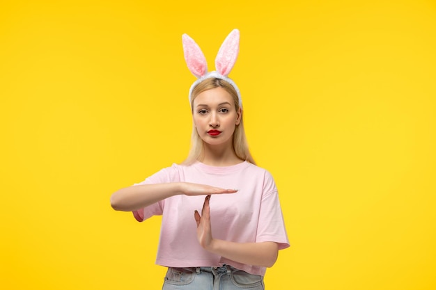 Easter lovely blonde adorable girl with pink bunny ears and red lipstick showing stop sign