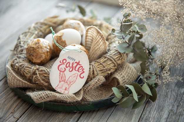 Easter still life with decorated Easter eggs and decorative nest on a wooden surface