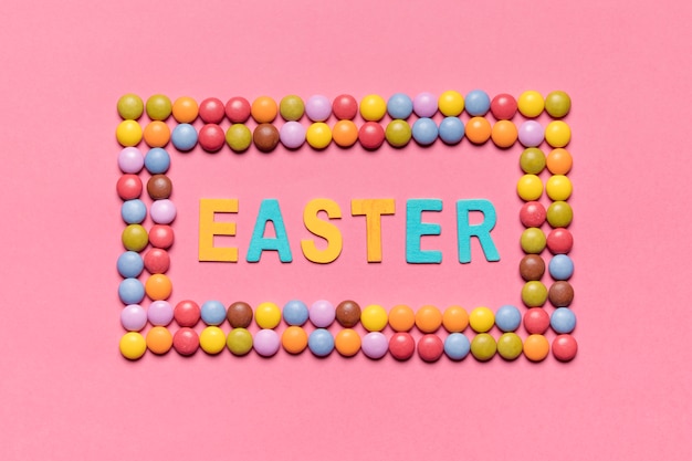 Free photo easter word inside the colorful gem candies frame over the pink backdrop