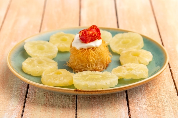 Free photo eastern pastry cookies inside plate with white cream dried pineapple rings on wooden table