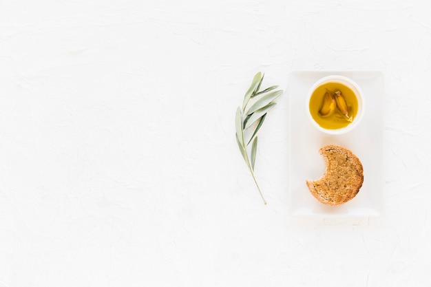 Free photo eaten bread with garlic clove in the oil bowl on white background