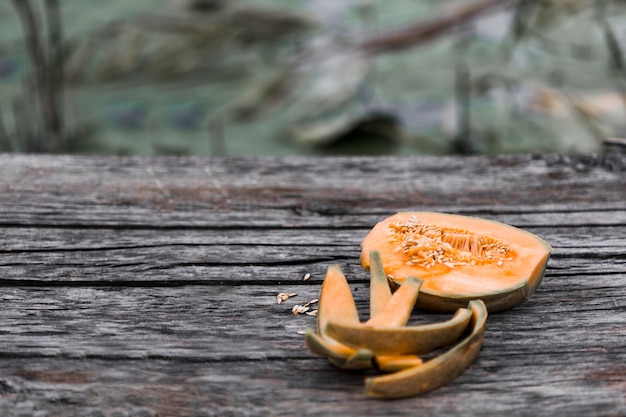 Eaten and halved musk melon on weathered wooden table