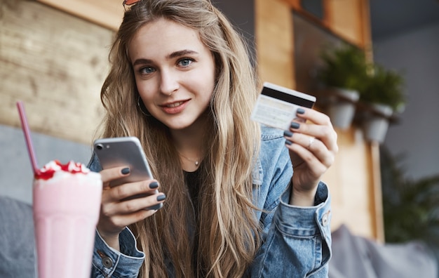 Eating out and candid people concept. Young blond woman paying f