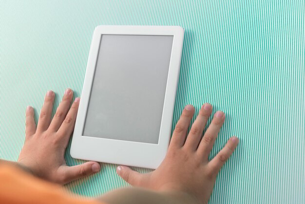 Free photo ebook reader over green background  being held by the hand of a child