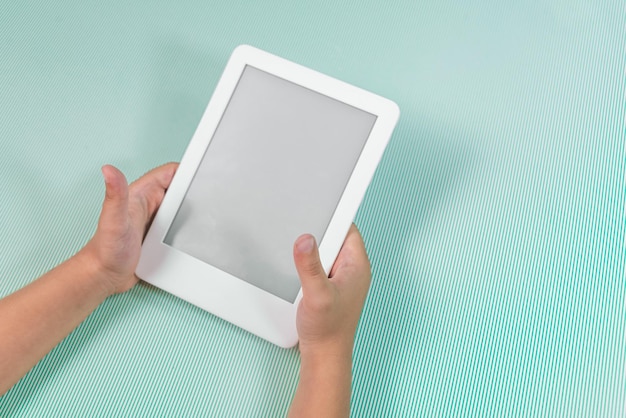 Free photo ebook reader over green background  being held by the hand of a child