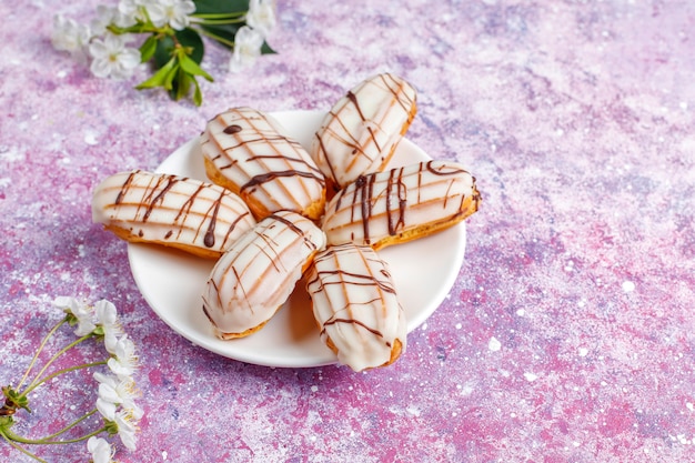 Eclairs or profiteroles with black chocolate and white chocolate with custard inside,traditional french dessert.top view.