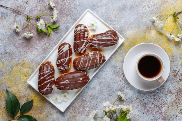 Free Photo eclairs or profiteroles with black chocolate and white chocolate with custard inside,traditional french dessert.top view.