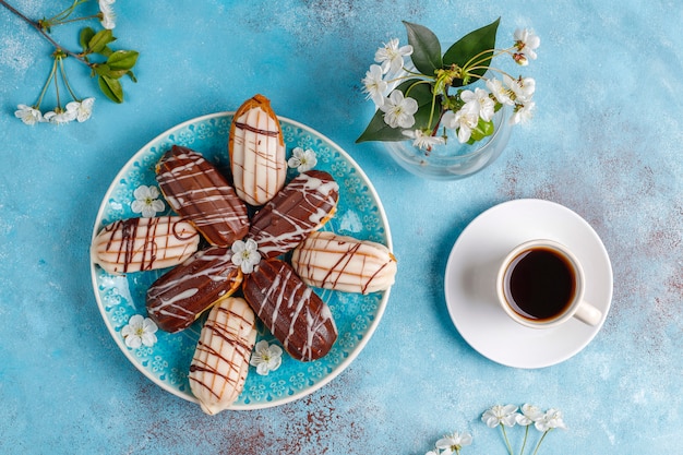 Free Photo eclairs or profiteroles with black chocolate and white chocolate with custard inside, traditional french dessert. top view. 