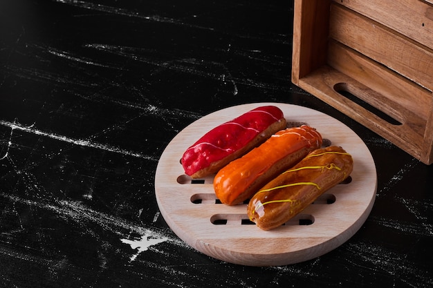 Free Photo eclairs with fruit sauces on the top served on a wooden board.