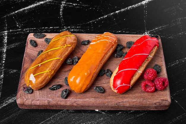 Free photo eclairs on wooden platter .