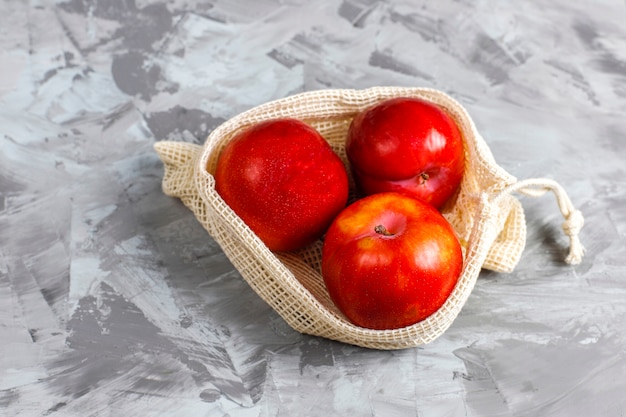 Eco-friendly simple beige cotton shopping bags for buying fruit and vegetables with summer fruits.