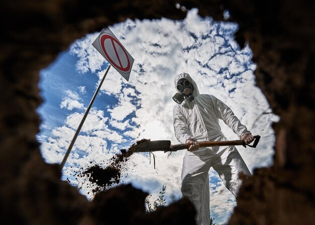 Ecologist digging pit by shovel and planting tree in polluted area