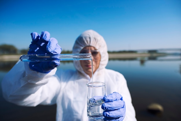 Free photo ecologist sampling water from the river with test tube