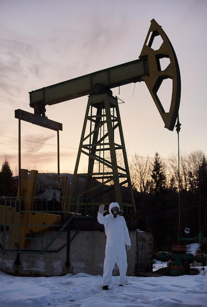 Ecologist standing near oil well pump jack