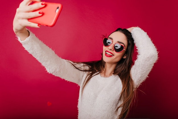 Ecstatic brunette girl plays with her hair while taking picture of herself