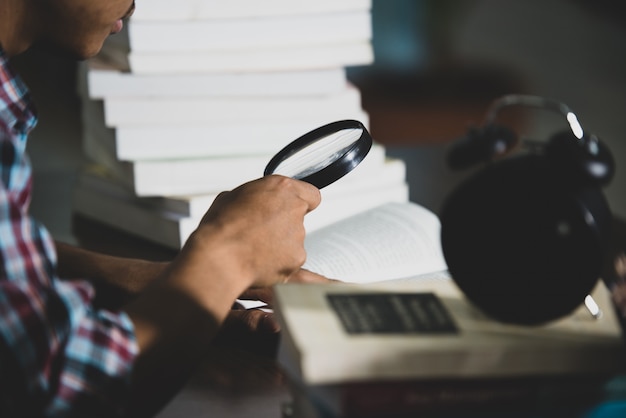 Free photo educational theme: close -up student looking through a magnifying glass to book