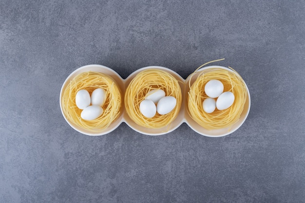 Free photo egg noodle nests with white candies in bowls.