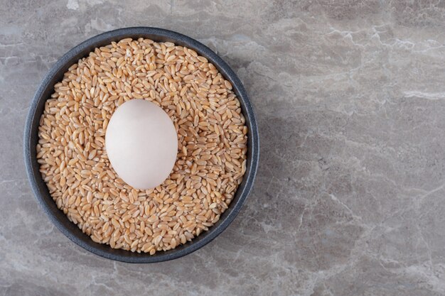 Egg and pile of barley on black plate.