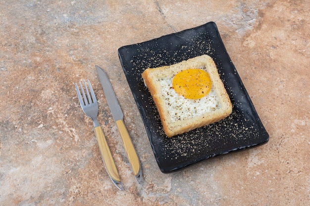 Free photo egg toast with spices on black plate with cutlery