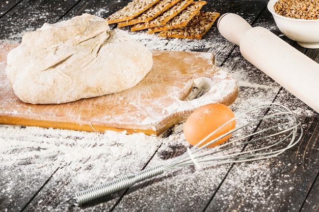 Free photo egg and whisker near the knead dough on chopping board