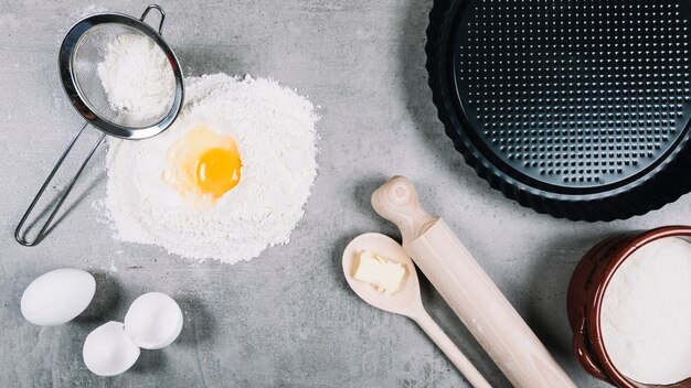 Egg york on flour on kitchen counter with baking utensil