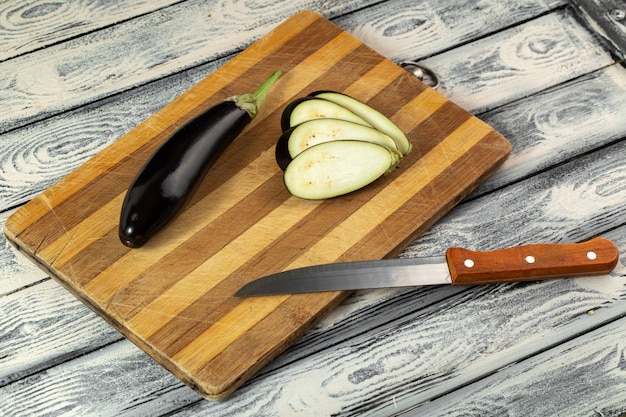 Eggplant dark fresh ripe mellow sliced on wooden desk and grey floor