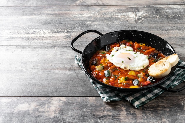 Free Photo eggplant and egg onions peppers served in frying pan on wooden table vegetable pisto manchego with tomatoes zucchini