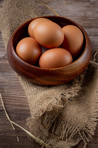 Eggs in cups on burlap with dry grass.