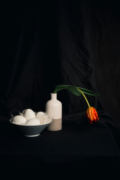 Free photo eggs and feathers near faded orange flower in vase