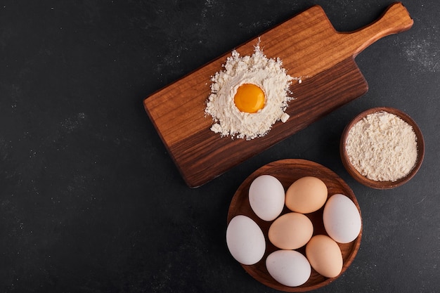 Free photo eggs and flour in wooden platters for bakery making.