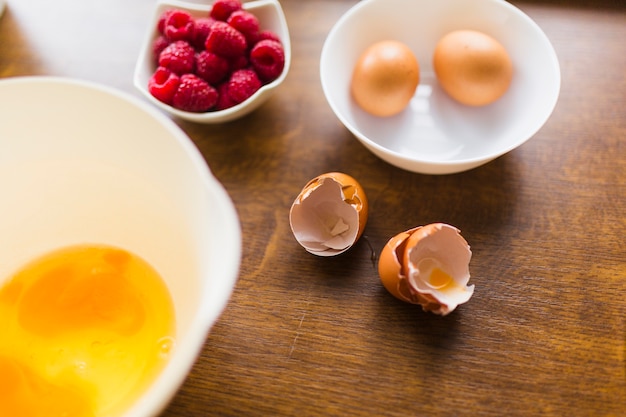 Eggshell near bowl with raw eggs