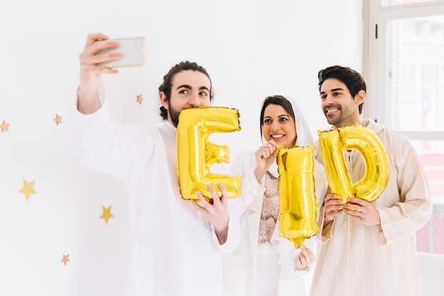 Free Photo eid al-fitr concept with friends showing letters