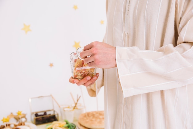 Free photo eid al-fitr concept with man holding jar of cookies