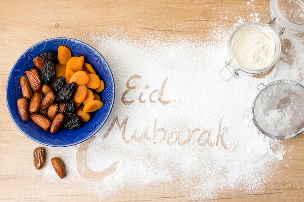 Free photo eid mubarak inscription on flour near dried fruits