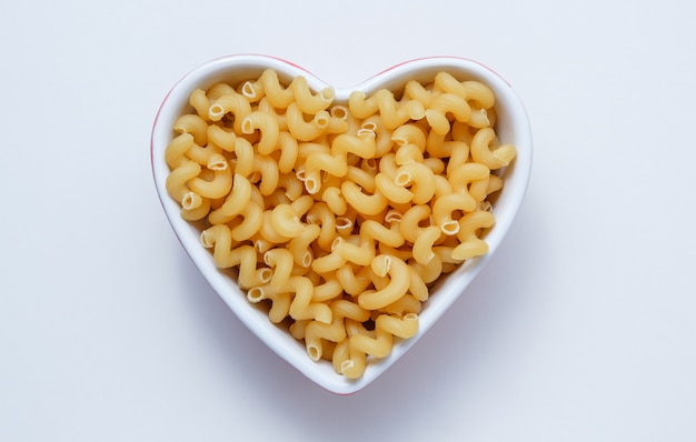 Free Photo elbow macaroni pasta in a heart shaped bowl top view on a white table