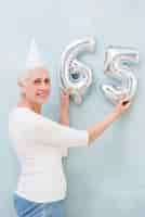 Free photo elder beautiful woman holding metallic foil balloon number on her birthday