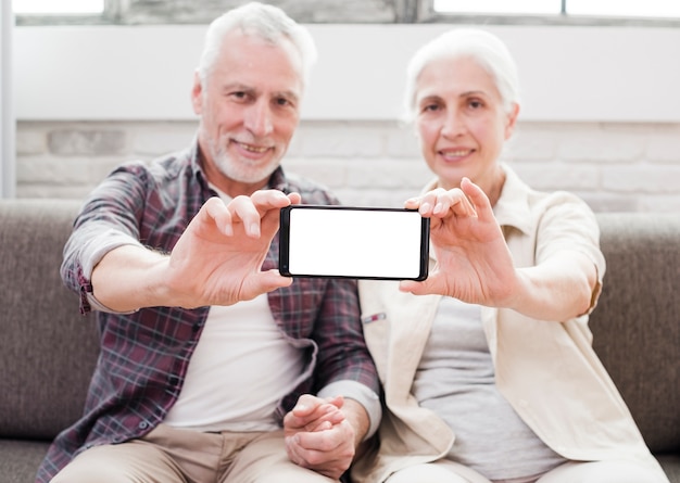 Free photo elder couple showing a smartphone