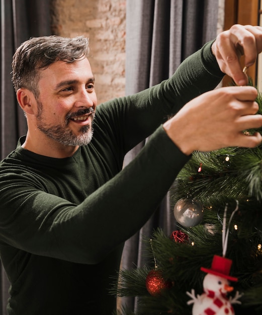 Elder man enjoying christmas tree decoration