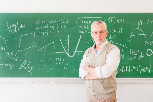 Elder professor standing near chalkboard in classroom 